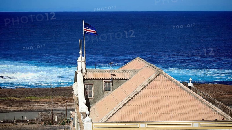 View from above of a building, City Hall, with a terracotta roof against the deep blue ocean with a waving Cape Verde flag, flag, Ponta do Sol, Santo Antao, Cabo Verde, Cape Verde, Cape Verde