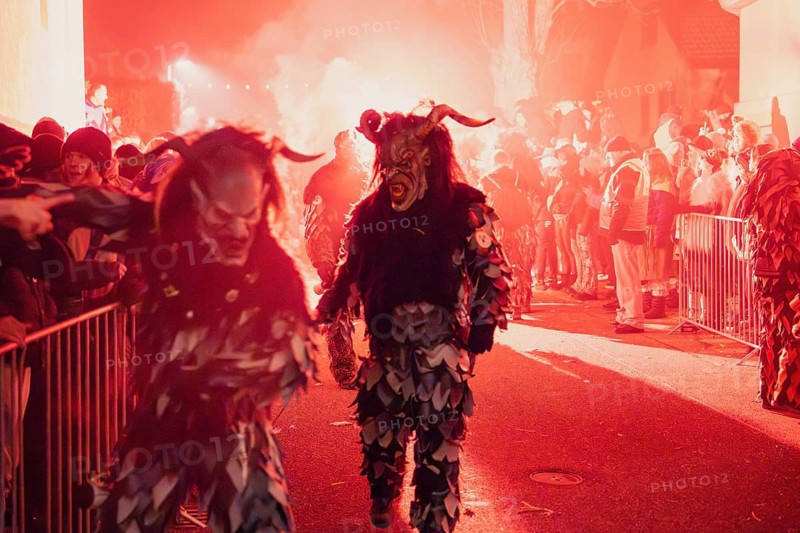 People in frightening costumes take part in a night-time festival under red light, carnival, Tiefenbronn, Enzkreis, Germany