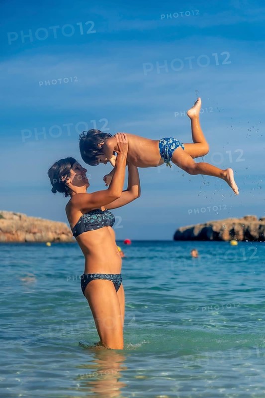 Mother and son enjoying summer holidays, playing in the turquoise clear water of cala domingos beach in mallorca, balearic islands, spain