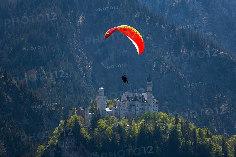 A paraglider glides over Neuschwanstein Castle against a mountainous backdrop, tandem, Schwangau near Füssen, Ostallgäu district, Swabia, Bavaria, Germany