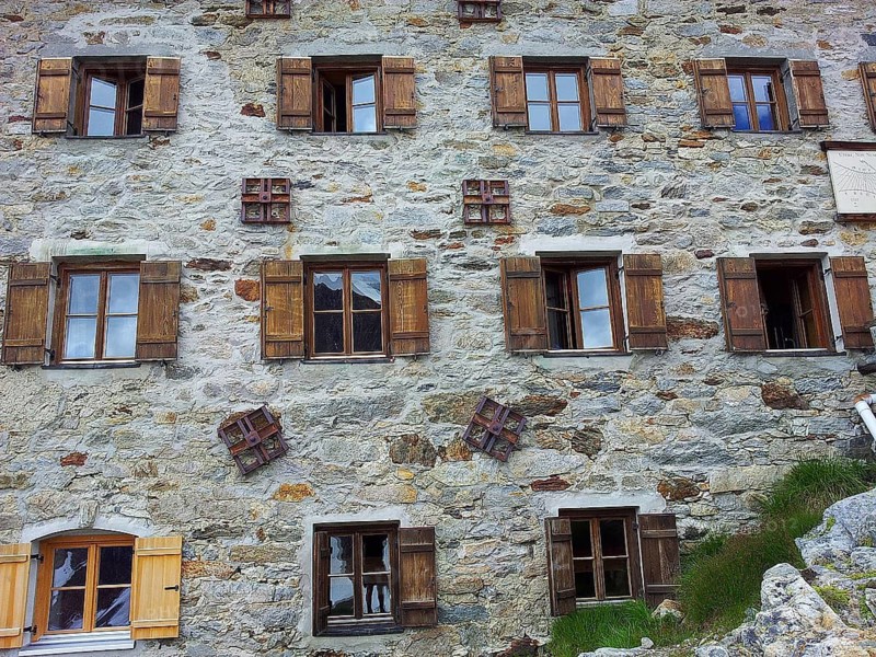 Exterior view of the Martin-bush-Hütte, rustic stone house with several windows in alpine surroundings, E5, hiking in the Alps, crossing the Alps, Austria