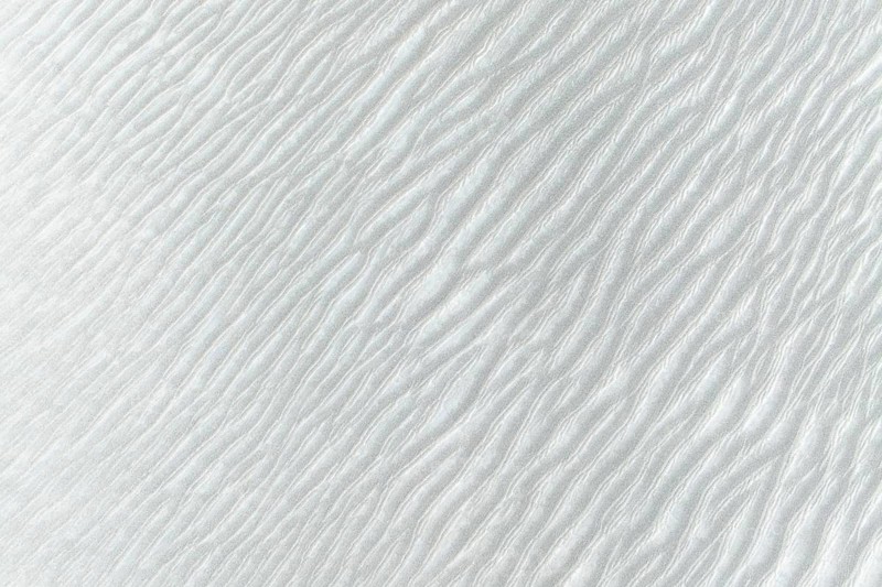 Intricate rippling sand patterns in La Puna desert create a captivating visual reminiscent of flowing water. Subtle light and shadow enhance the natural artistry of the scene