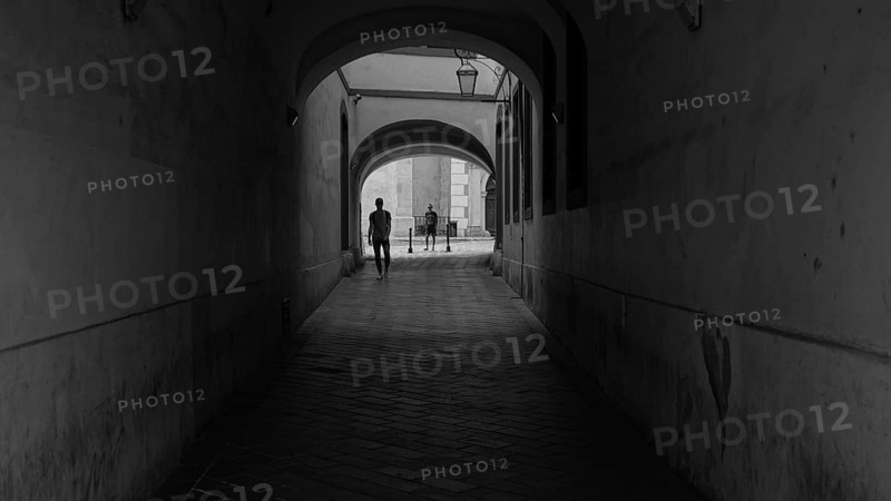 Dark passageway with people heading for a bright exit, monochrome street scene from Bratislava, Slovakia