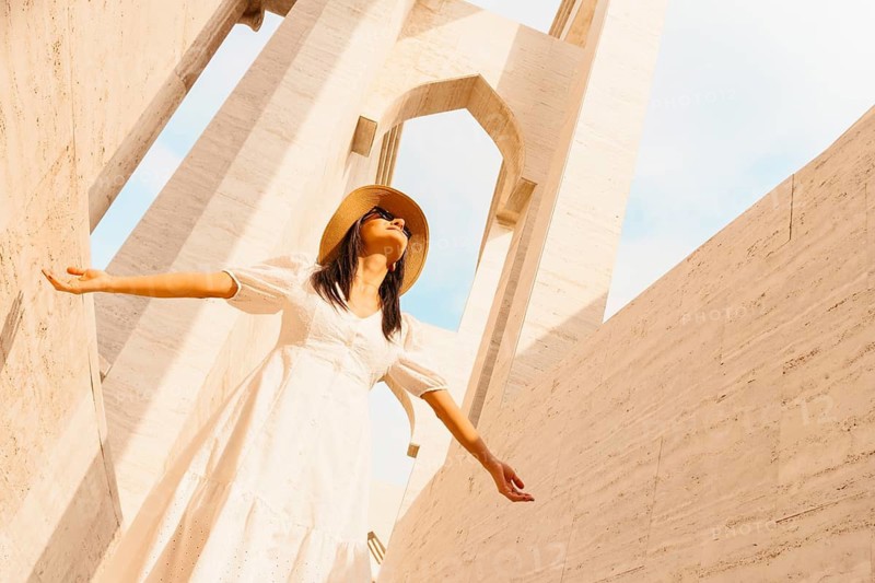 Doha Qatar Katara Cultural Village woman in white dress walking amphitheater traditional architecture arches stone columns heritage landmark tourism Middle East culture travel lifestyle