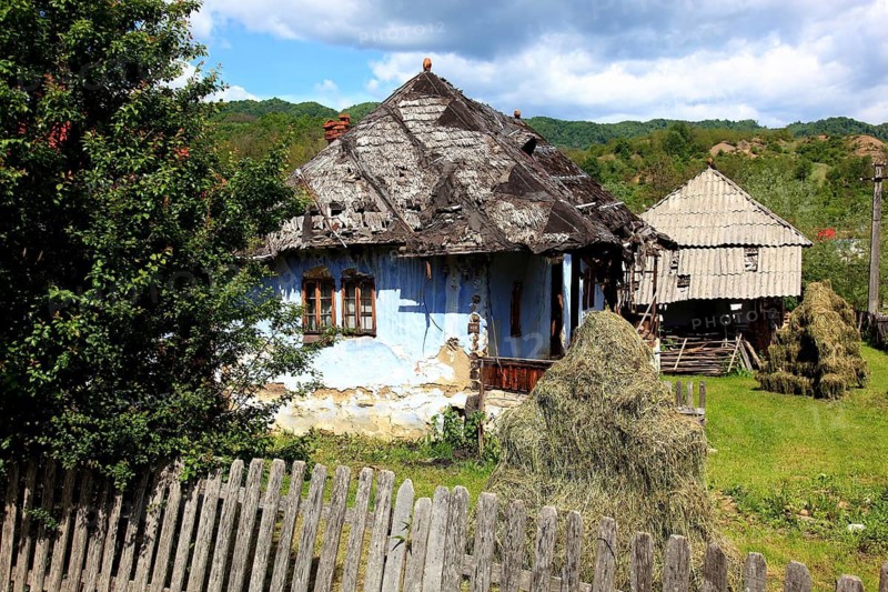 Traditional Romanian farmhouse that is in a dilapidated or abandoned state. The eye-catching light blue color of the outer walls is common in many Romanian villages, such houses are characteristic of rural regions in Romania, particularly Transylvania, Transylvania