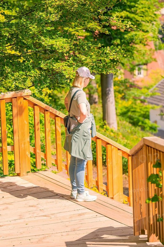 A woman stands on a wooden platform and looks over the green valley, Panorama Holzsteg, Calw, Black Forest, Germany