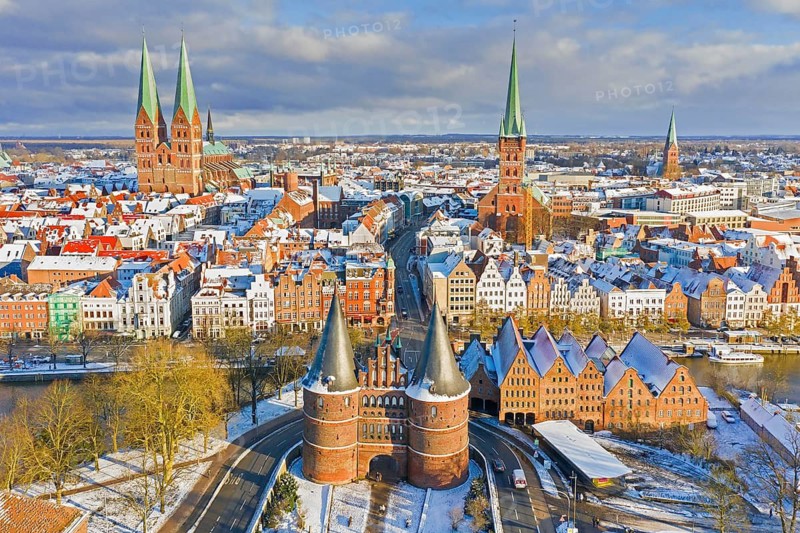 Aerial view over Holsten Gate, St. Mary's and St. Peter's Church and old town of Hanseatic City Lübeck in winter, Schleswig-Holstein, Germany