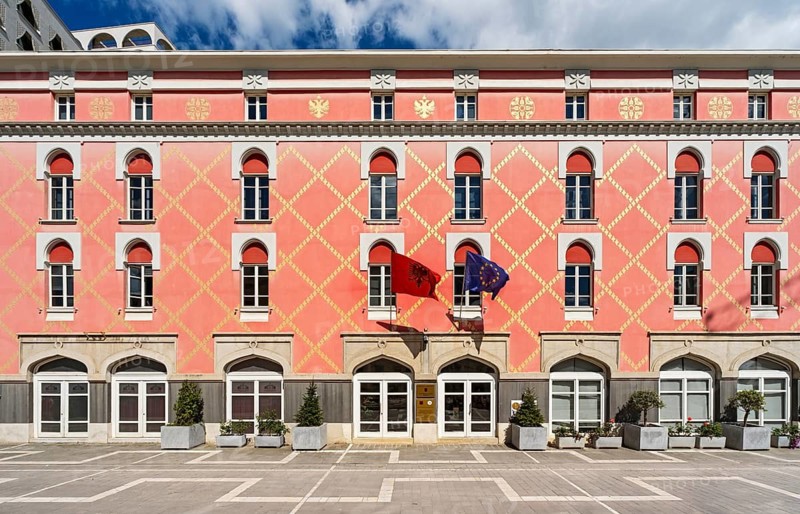 The distinctive pink facade with yellow geometric patterns of the Ministry of Agriculture featuring the Albanian and EU flags, Tirana, Albania