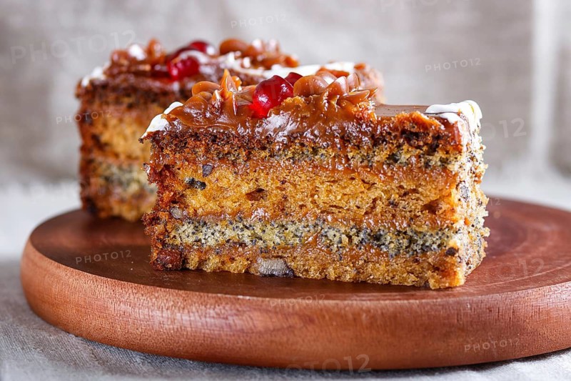 A piece of cake with caramel cream and poppy seeds on a wooden kitchen board. close up, selective focus, white background
