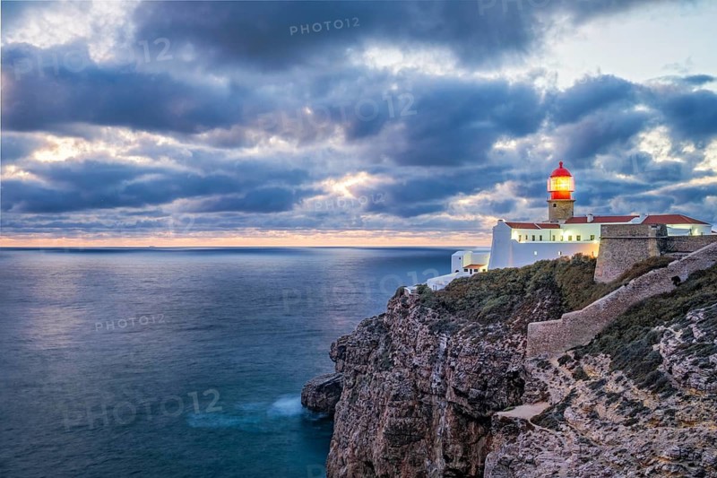 View of the Lighthouse of Cabo de Sao Vicente in Sagres, Algarve, Portugal, at evening with clifftop buildings and Atlantic ocean