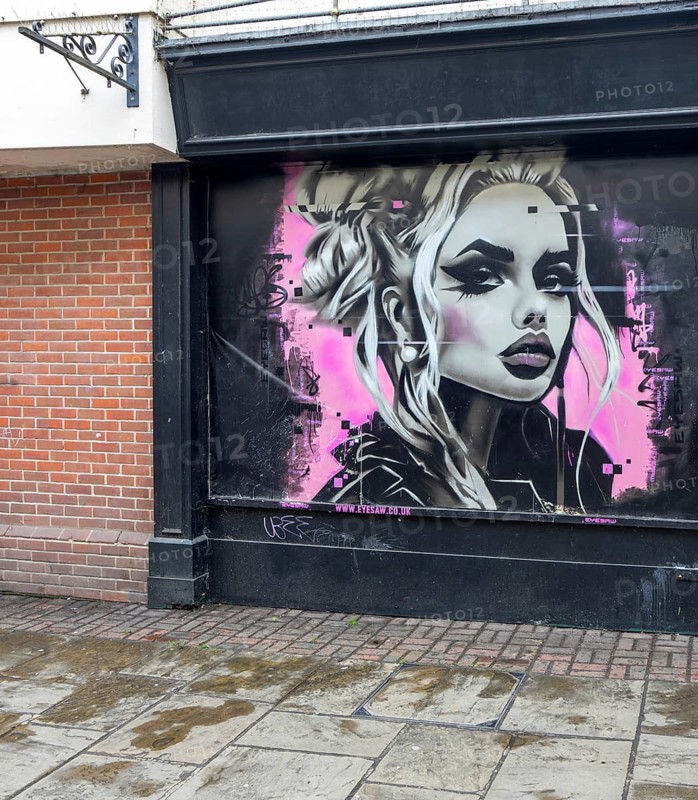 Street art mural of young woman Phantom Trace on shop wall, Colchester, Essex, England, UK by artist Eyesaw 2025