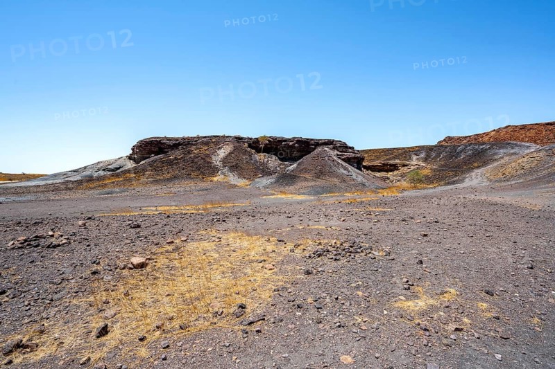 Dry landscape with yellow grass and black volcanic hills, Burnt Mountain, Damaraland, Kunene, Namibia