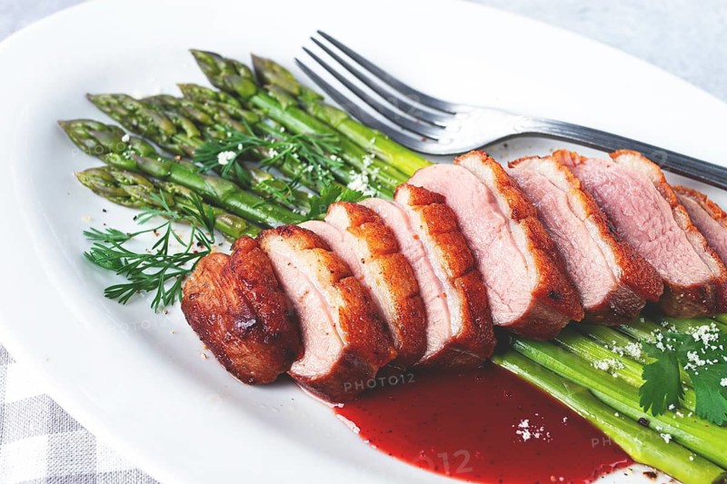 Roast duck breast, with asparagus, with red sauce, on a white plate, homemade, no people