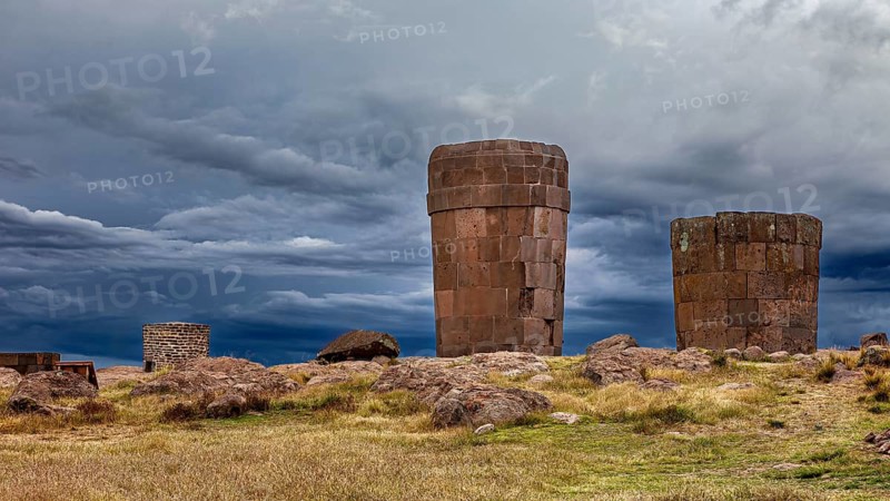 Old stone towers against a dramatic sky in a barren landscape, The Chullpas of Sillustani near Puno in Peru
