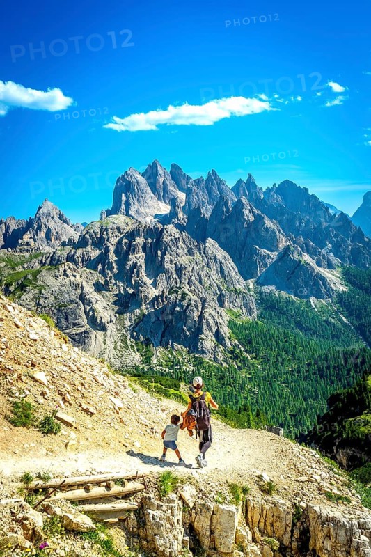 Tourists enjoying a scenic hike on the tre cime di lavaredo trail, surrounded by the breathtaking peaks of the dolomites in summer