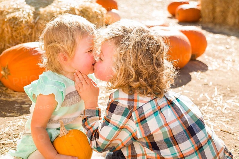 Sweet Little Boy Plays with His Baby Sister in a Rustic Ranch Setting at the Pumpkin Patch