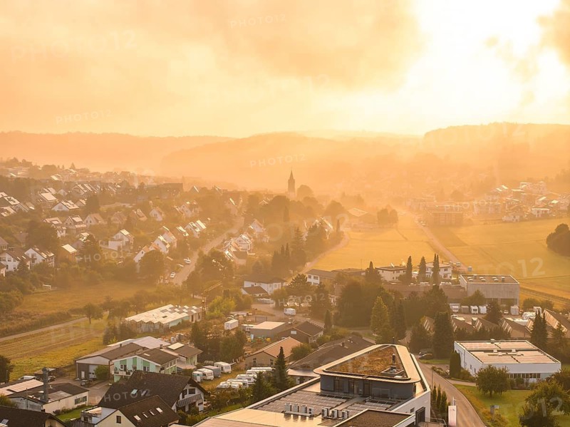 A village at dawn with wafts of mist, illuminated by the rising sun, Gechingen, Black Forest, Germany