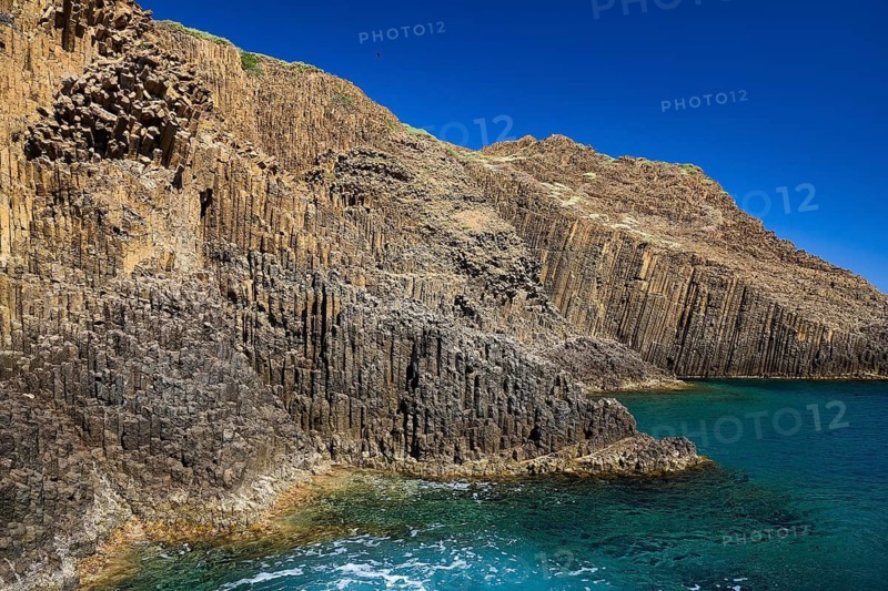 Steep cliffs with unique basalt columns on the edge of a calm ocean, Glaronisia, Glaronesia, Milos, islets, hexagonal basalt columns, north of Milos, destination by boat, Cyclades, Greek Islands, Greece