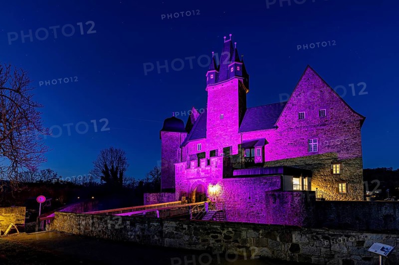 A splendidly illuminated castle in the dark, lit up by deep pink light, Spangenberg Castle
