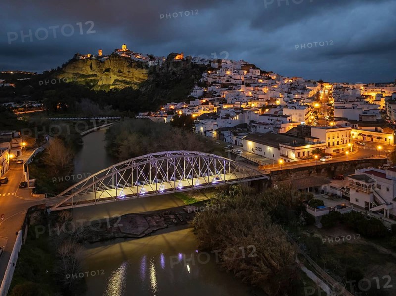 The hilltop White Town of Arcos de la Frontera on a limestone rock above the Guadalete river. At dusk. Aerial view. Drone shot. Arcos de la Frontera, Cádiz province, Andalusia, Spain