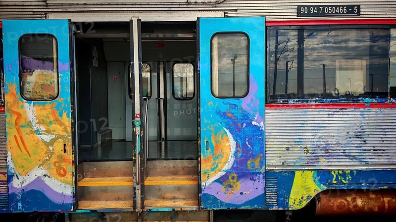 Colourful train with open doors and graffiti on colorful train walls, Faro railway station, Algarve, Portugal