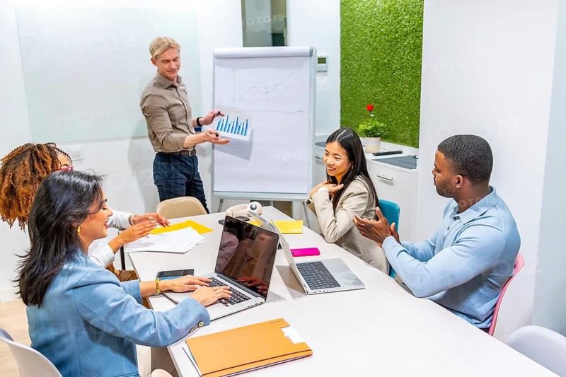 Business team analyzing positive data charts during a presentation in a modern coworking office