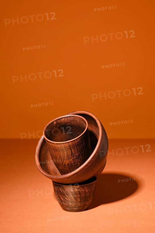 Composition with clay bowls on orange background with hard shadow