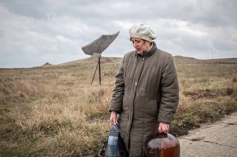 Woman carrying drinking water home, in the background memorial Kerch-Eltigen operation in the Second World War, Kerch, Crimea, Ukraine