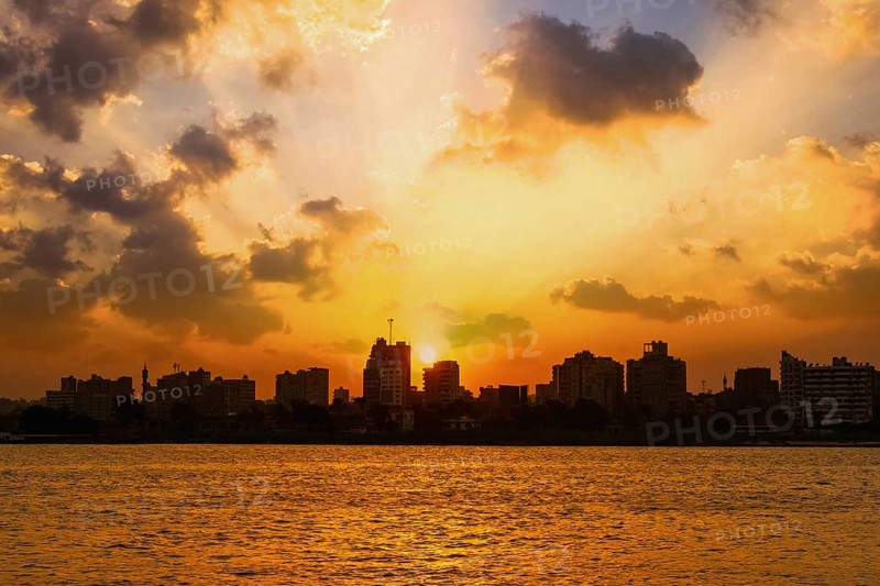 Orange sunset on the Nile river, the sun hides in the buildings of the city of Cairo in the background. Africa