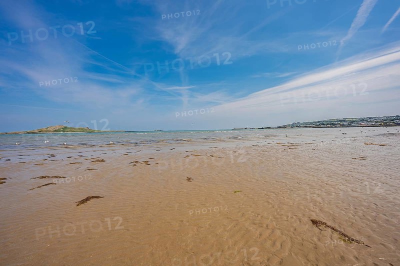 Wide beach landscape with sea view and cloudy sky, low tide, Howth beach, Ireland