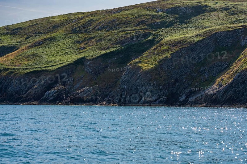 Green hills rise above sparkling blue coastal waters, cliff tour, Howth, Ireland