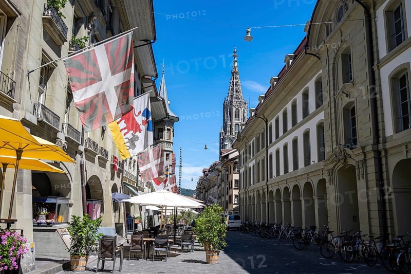 Münstergasse with historic houses decorated with flags, tower of the Bernese Minster in the back, old town, Bern, Canton of Bern, Switzerland
