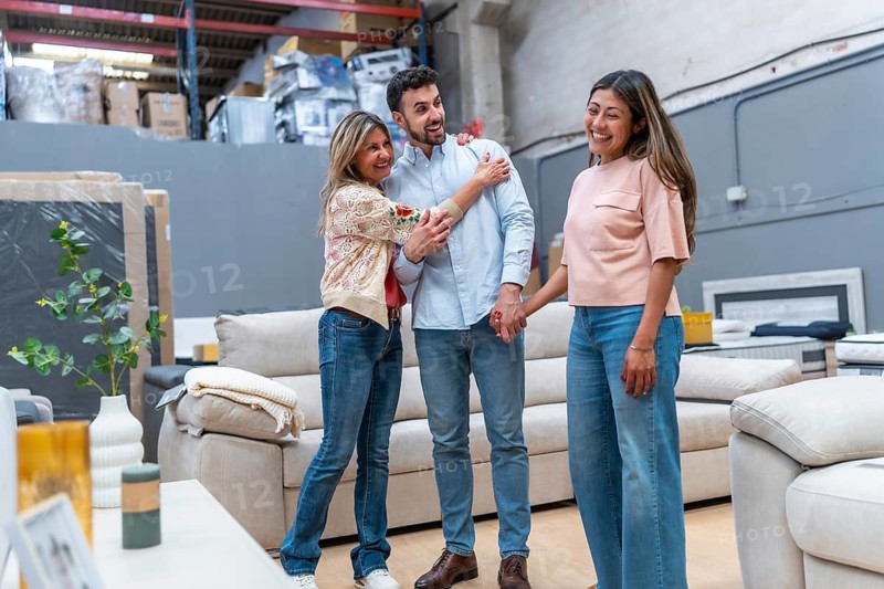 Adults and young woman smiling while choosing new home furniture in a showroom, discussing sofas and decor, enjoying shopping together and making purchase decisions for their living room