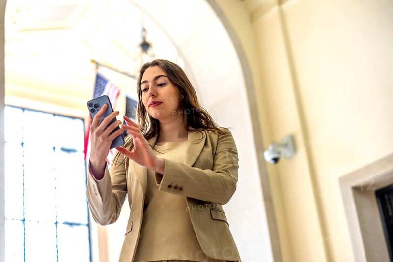 Young professional woman in formal wear interacting with her smartphone, checking messages or browsing content inside a modern interior building in manhattan