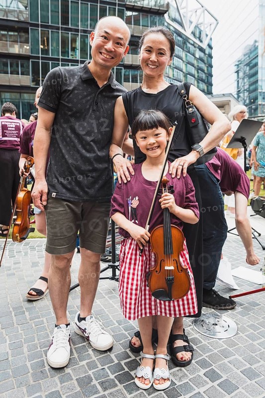Seven-year-old Chizuru Kujime, pictured here with her parents, performs with a ‘Symphonic Mob' organised by the German Symphony Orchestra (DSO) under the baton of its future principal conductor, Kazuki Yamada, on 20 June 2026. Professional and amateur musicians performed works by Brahms, Mozart, Haydn and Bizet together at the former Sony Centre in Berlin's Potsdamer Platz
