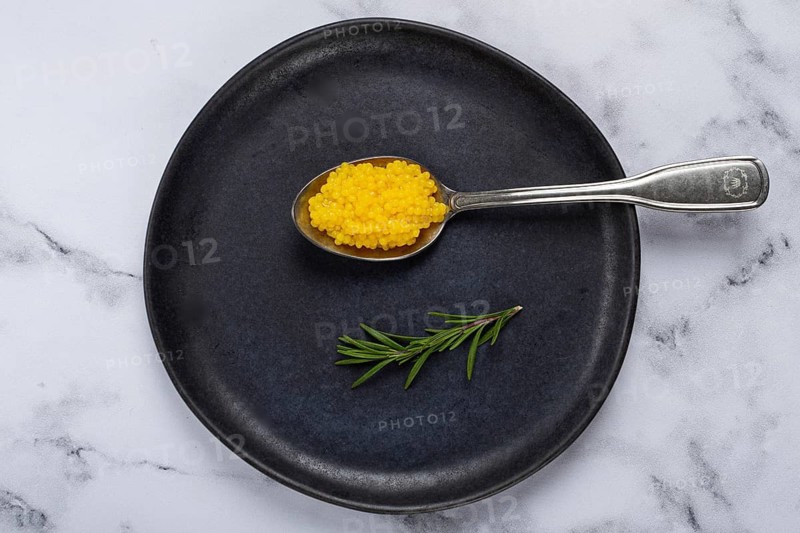 Pearl yuzu, yuzu caviar - pearl, on a spoon, top view, on a dark gray plate, there are no people.