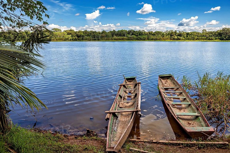 Two wooden boats on the shore of a calm lake with a wooded background and clear blue sky, The Beni River near Rurrenabaque in the Amazon Basin in Bolivia