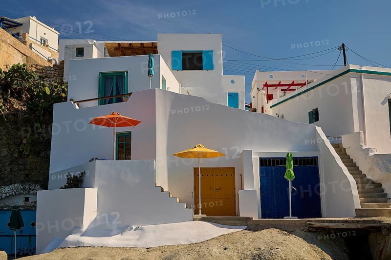Whitewashed buildings with colored doors and umbrellas, under blue skies in Mediterranean surroundings, Syrmata, boat garages, boathouse, boathouses, beach house, Goupa, Goypa, Goupa Kara, Kimolos, Cyclades, Greek Islands, Greece