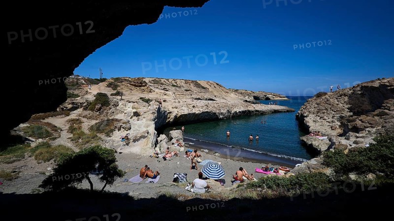 People relaxing on the beach in a rocky bay in the shade with a view of the open sea, Kapras, Kapros, Beach, Kapros Beach, Caves, Paralia Kapros, Milos, Cyclades, Greek Islands, Greece