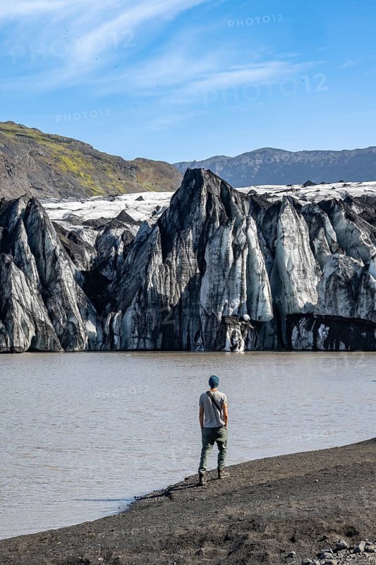 Tourist at the lakeside of a glacier lagoon, glacier tongue with crevasses and lake, Sólheimajökull, South Iceland, Iceland