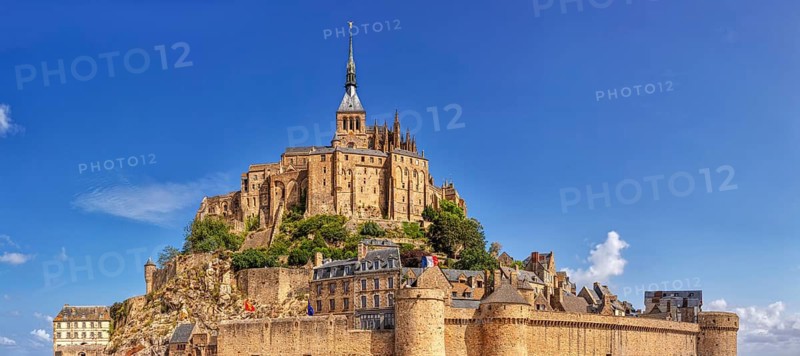 Historic monastery on a rocky hill with stone walls and towers under a clear sky, Le Mont-Saint-Michel