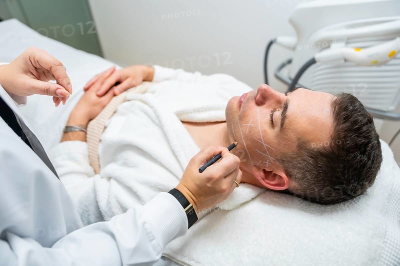 Doctor marks man's face with precise guidelines for cosmetic treatment in a modern clinic, conveying professional care, preparation, and a calm, clinical aesthetic for facial rejuvenation