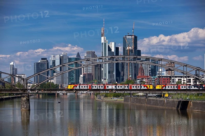 The river Main with regional railway on the Deutschherrnbrücke and the skyline of Frankfurt am Main, Hesse, Germany