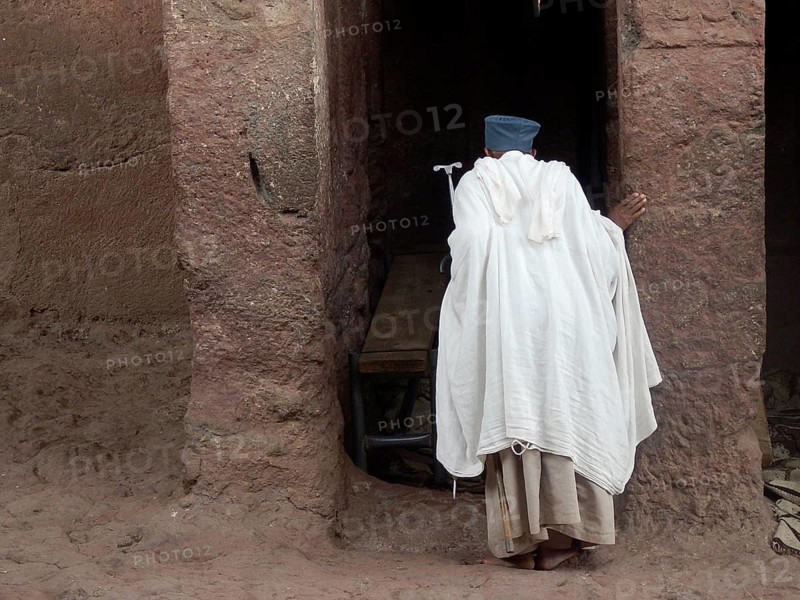 A man in traditional clothing stands at the entrance of an old stone structure, UNESCO World Heritage Site, Bet Giyorgis, Lalibela Rock Church, Ethiopia