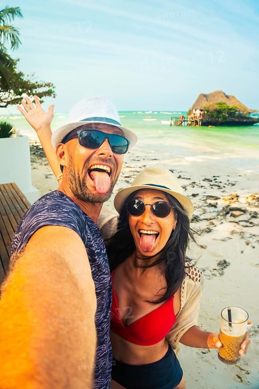 Playful couple taking funny beach selfie in Zanzibar Tanzania, tropical vacation, carefree travel lifestyle, Indian Ocean coastline, joyful holiday moments