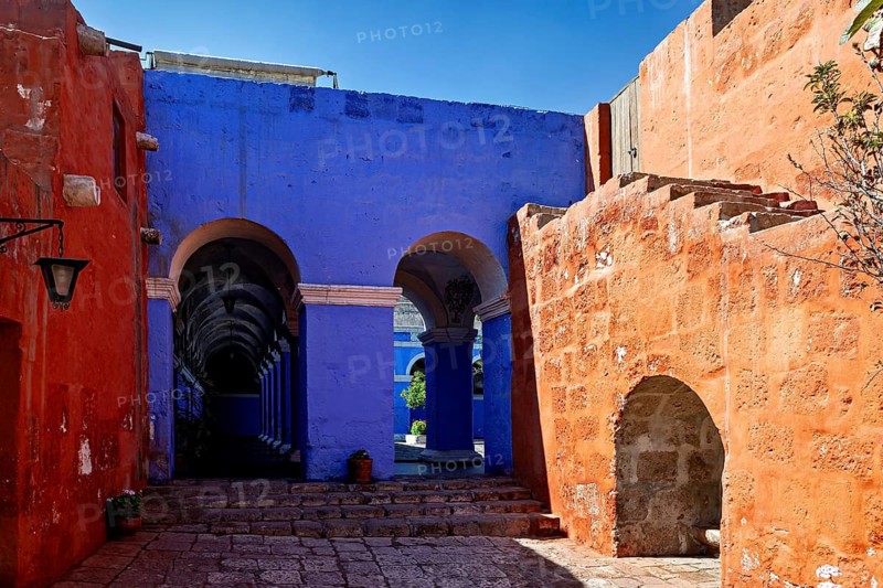 An architectural scene with eye-catching blue and red walls and elegant arches, The Santa Catalina Monastery in Arequipa in Peru