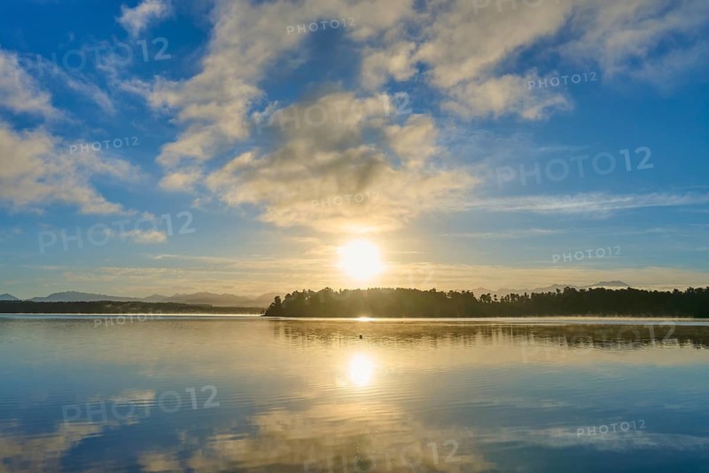Sunrise over a calm lake, cloudy sky and light reflections, Lake Mahinapua, Ruatapu, South Island, New Zealand