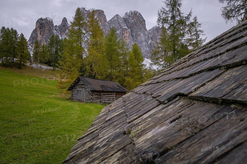 View over a wooden roof of a mountain hut to a part of the Geisler group from the Gampenwiese, Dolomites, snow, Puez-Geisler nature park Park, St. Magdalena, Funes, Villnößtal, South Tyrol, Italy