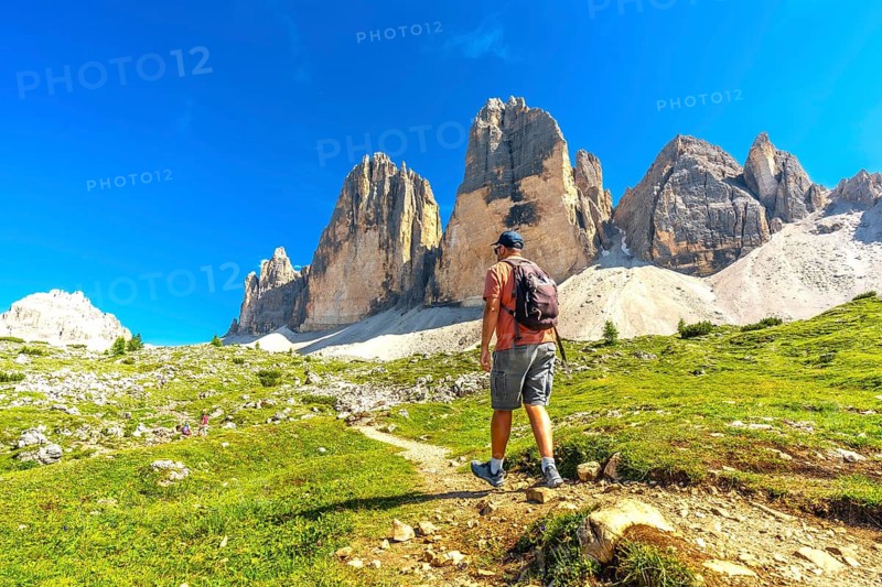 Tourist enjoying a scenic hike on the tre cime di lavaredo trail amidst the breathtaking peaks of the dolomites in summer