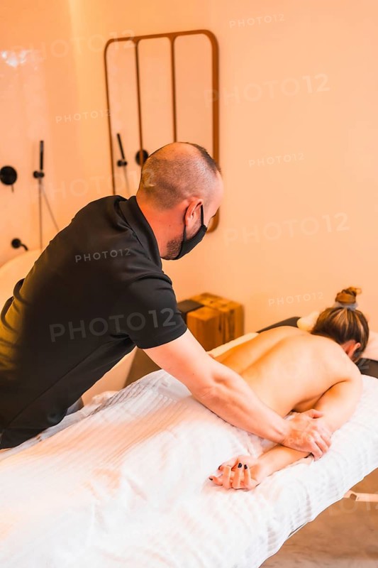 Home massage, performing a massage at the client's home, vertical photos. With a face mask in the coronavirus pandemic